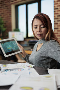 Woman with tablet pc sitting at desk in office