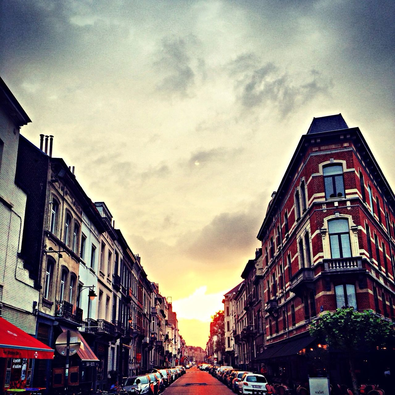 architecture, building exterior, built structure, sky, car, transportation, street, cloud - sky, city, residential building, residential structure, sunset, land vehicle, the way forward, building, diminishing perspective, cloudy, road, cloud, house