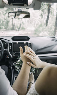 Picture of man and woman in car. married couple holding hands, newly wed couple's hands, rings.