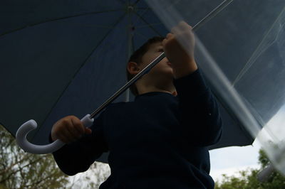 Low angle view of boy holding umbrella