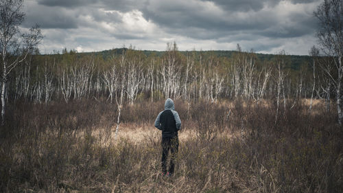 Rear view of man standing on field against sky