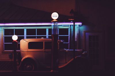 Vintage car on illuminated street against building at night