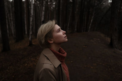 Profile view of woman standing against trees in forest