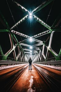 Rear view of man on illuminated tunnel at night