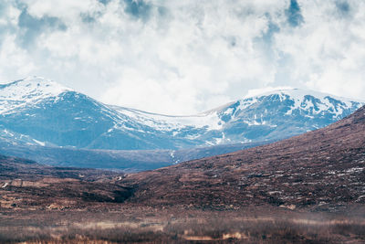 Scenic view of snowcapped mountains against cloudy sky