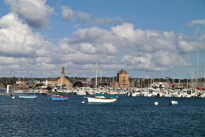 Sailboats moored in sea against buildings in city