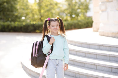 Smiling sweet happy little kid girl 5-6 year old wear casual clothes and backpack. 