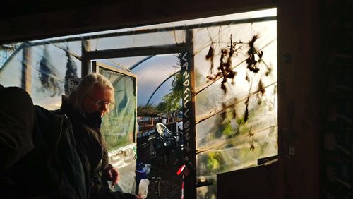 Side view of man looking through window