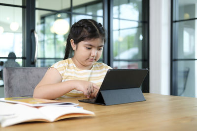 Young woman using phone while sitting on table