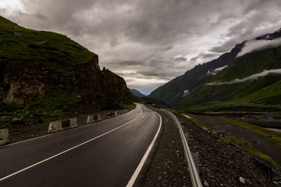 Empty road under cloudy sky