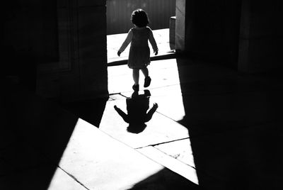 Rear view of girl walking on tiled floor