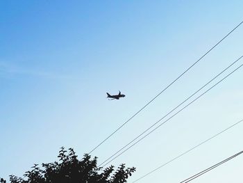 Low angle view of airplane flying against clear blue sky