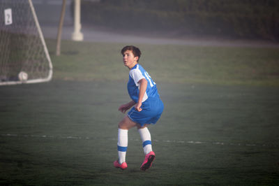 Teen soccer player ready to defend on a foggy field