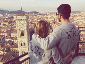 Rear view of couple looking at giotto campanile from observation point in city