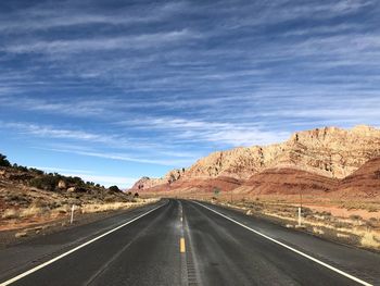 Road leading towards mountains against sky