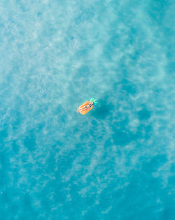 Drone view of woman relaxing on raft in sea