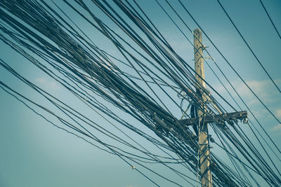 Low angle view of electricity pylon against blue sky