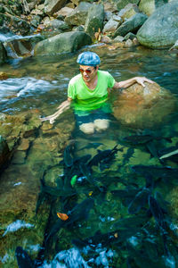 Man sitting by rock and fishes in sea