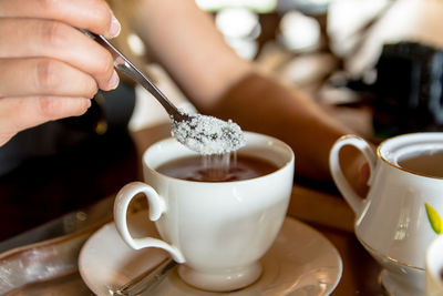 Close-up of hand holding coffee cup on table