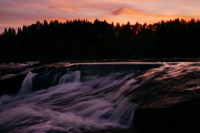 Scenic view of waterfall in forest against sky