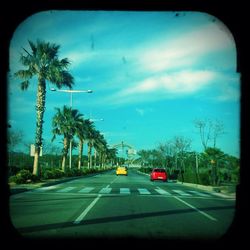 Cars on road against cloudy sky