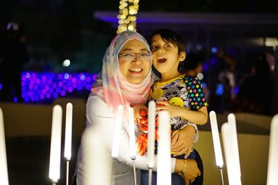 Portrait of mother with son standing in illuminated room