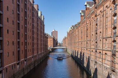 Canal amidst buildings against clear sky