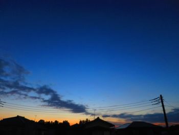 Low angle view of silhouette trees against blue sky