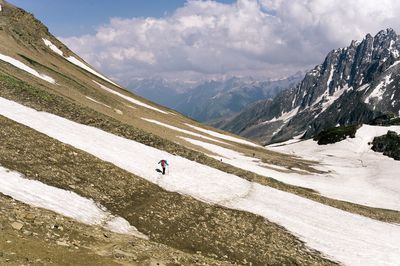 Rear view of person hiking on mountain against sky