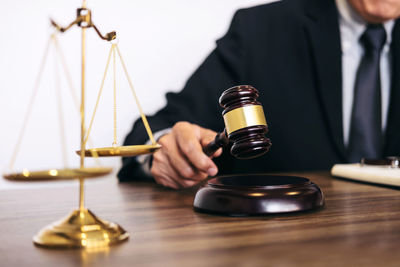 Midsection of lawyer holding gavel at desk in courthouse