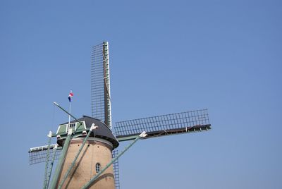 Low angle view of traditional windmill against clear blue sky