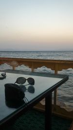 Close-up of sunglasses on table at beach during sunset