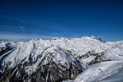 Scenic view of snowcapped mountains against blue sky