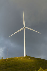 Low angle view of windmill on field against sky
