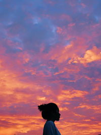 Low angle view of woman against cloudy orange sky during sunset