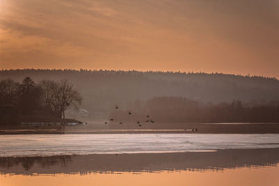 Scenic view of lake against sky at sunset