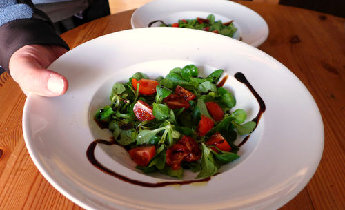 Cropped image of hand holding salad in plate