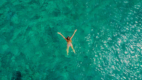 Aerial photo of girl swimming in blue water on vacation in the mediterranean.