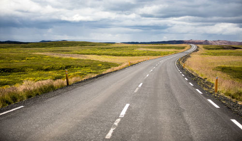 Road passing through landscape against cloudy sky