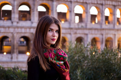 Portrait of beautiful woman standing against historical building