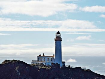 Lighthouse by building against sky