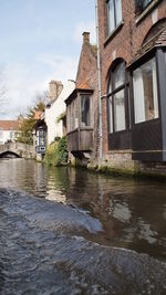 Houses by river against sky