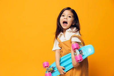 Portrait of young woman holding gift against yellow background