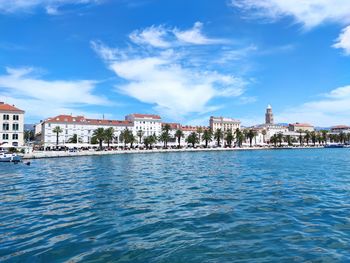 Sea by buildings against blue sky