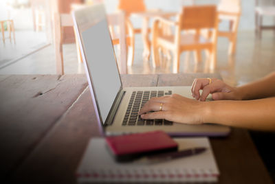 Cropped hands of woman using laptop on table