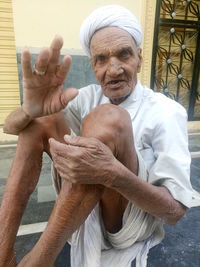 Portrait of senior man sitting against wall