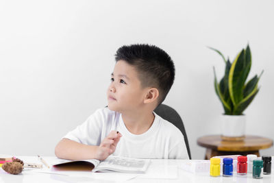 Portrait of boy looking at table against white background