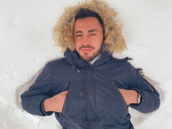 Portrait of man lying on snow