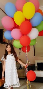 Portrait of smiling girl holding colorful balloons at home