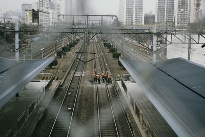 Construction worker working on railroad tracks seen through chainlink fence
